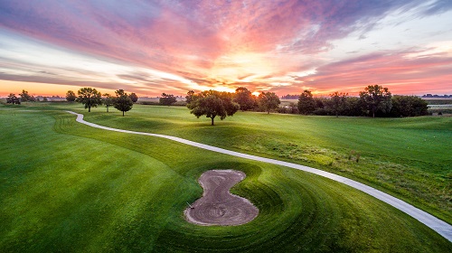 Cart path and bunker on golf course at sunset