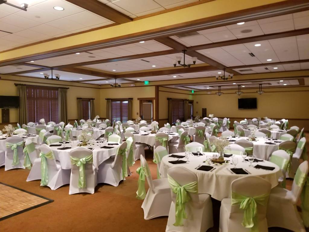 Wedding reception banquet seating with green ribbon bows on chairs